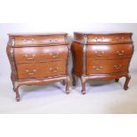 A pair of oak veneered bombe shaped commodes with three long drawers and brass mounts, 34" x 17½",