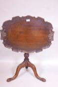 A mahogany tilt top occasional table, with dished top with shaped edge, raised on a carved turned