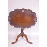 A mahogany tilt top occasional table, with dished top with shaped edge, raised on a carved turned