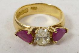 A 22ct yellow gold diamond and ruby ring, the central oval cut diamond ring flanked by two pear