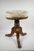 A Victorian mahogany revolving piano stool on a turned column, fluted tripod legs and brass pawed