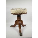 A Victorian mahogany revolving piano stool on a turned column, fluted tripod legs and brass pawed