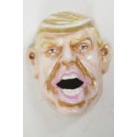 A cast iron wall mounted bottle opener modelled as Donald Trump, 4" long