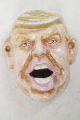 A cast iron wall mounted bottle opener modelled as Donald Trump, 4" long