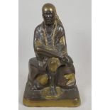 A Chinese bronze figure of a seated sage with gilt and patinated decoration, 11" high