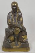 A Chinese bronze figure of a seated sage with gilt and patinated decoration, 11" high