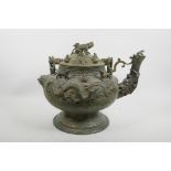 A Chinese bronze kettle with a dragon mask spout, dragon decoration to side and the cover