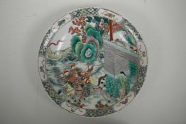 A Chinese famille verte porcelain charger decorated with warriors on horseback leaving a dwelling, 6