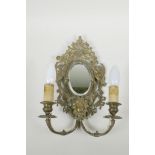 A brass two branch wall sconce with an oval mirror flanked by cherubs, converted for electricity,