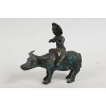A small Chinese bronze figurine of a boy playing the flute whilst sitting on the back of a