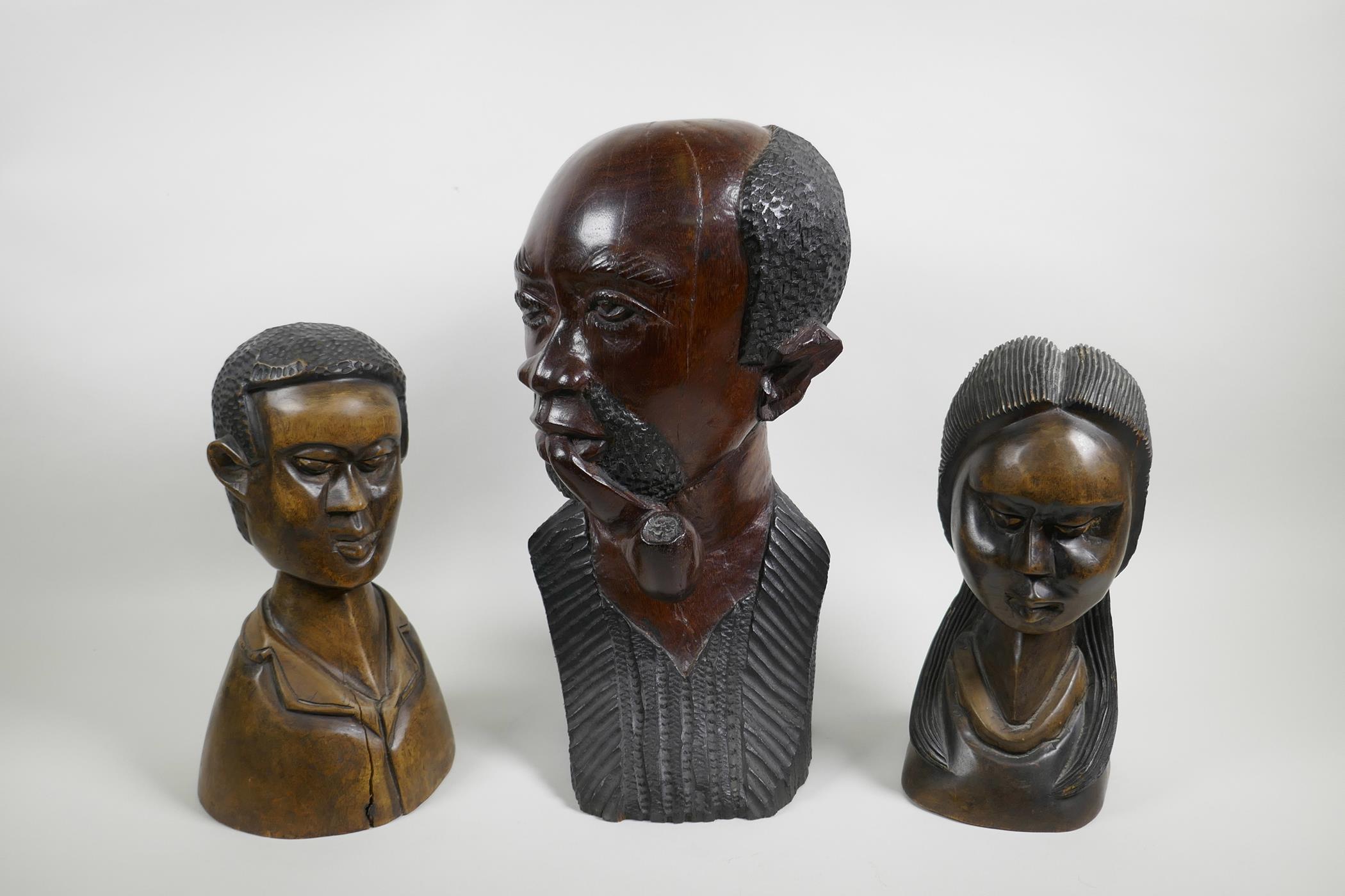 An African carved wood bust of a pipe smoking gentleman together with a pair of carved hardwood