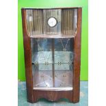 A mid C20th Hubbinet walnut corner display cabinet, with mirrored back and inset clock, and two