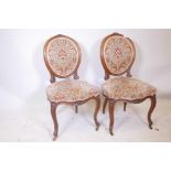 A pair of C18th walnut side chairs with spoon shaped backs and fine carved decoration, raised on