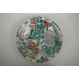 A Chinese famille verte porcelain charger decorated with warriors on horseback leaving a dwelling, 6