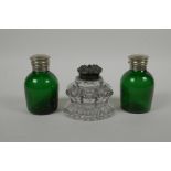 A heavy cut glass inkwell, with a bronze cap, together with two green glass ink pots with silver pla