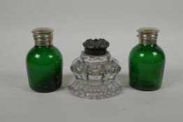 A heavy cut glass inkwell, with a bronze cap, together with two green glass ink pots with silver pla