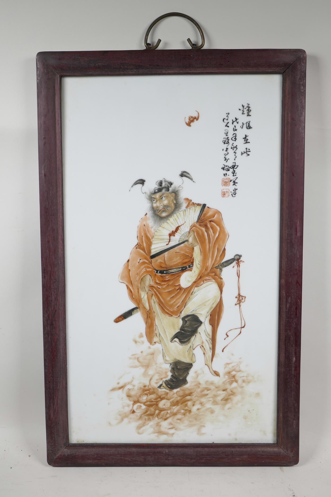 A Chinese polychrome porcelain panel decorated with a red robed Immortal, mounted in hardwood frames