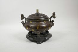 A Chinese two handled bronze censer on tripod supports with gilt splash decoration, a turned and car