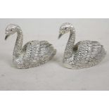 A pair of silver plated salt and peppers cast in the form of swans with red stone set eyes, 2" long