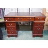 A Victorian style mahogany five drawer pedestal desk with six drawers and a cupboard, with leather i