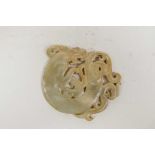 A Chinese white jade pendant with carved and pierced dragon decoration, 3" diameter