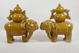 A pair of Chinese ochre glazed porcelain elephants carrying double gourds, 10" high