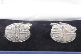 A pair of silver cufflinks with chased and engraved decoration of golfers