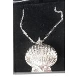 A silver clam shell locket on a silver chain