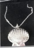 A silver clam shell locket on a silver chain