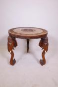 A Burmese hardwood occasional table on carved elephant head feet, the tabletop with carved detail of