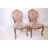 A pair of C18th walnut side chairs with spoon shaped backs and fine carved decoration, raised on cab