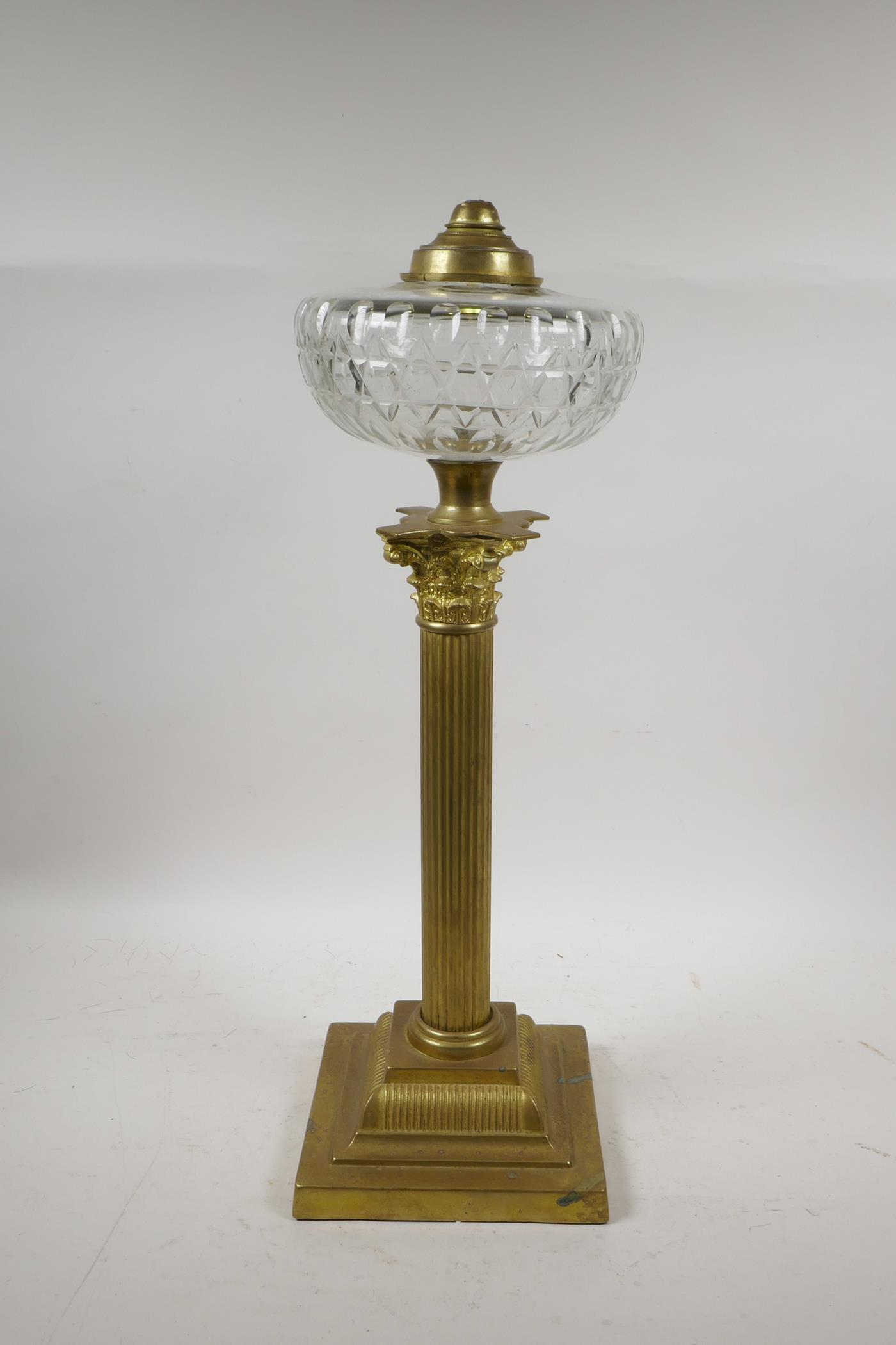 A brass Corinthian column adapted oil lamp with a glass reservoir, 20" high