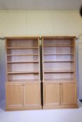 A pair of contemporary light oak veneered open bookcases with two cupboards below, in two sections,