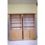A pair of contemporary light oak veneered open bookcases with two cupboards below, in two sections,
