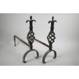 A pair of wrought iron fire dogs with pierced spiral finials, 17½" high, 17" long