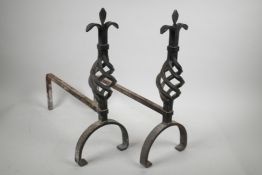 A pair of wrought iron fire dogs with pierced spiral finials, 17½" high, 17" long
