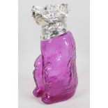 An amethyst glass decanter in the form of a seated bear with silver plated collar and head, 9" high