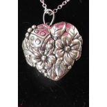 A heart shaped silver locket embossed with roses on a silver chain