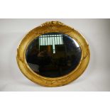 An oval gilt gesso mirror with reeded frame, surmounted by carved swags and a tied ribbon carving to