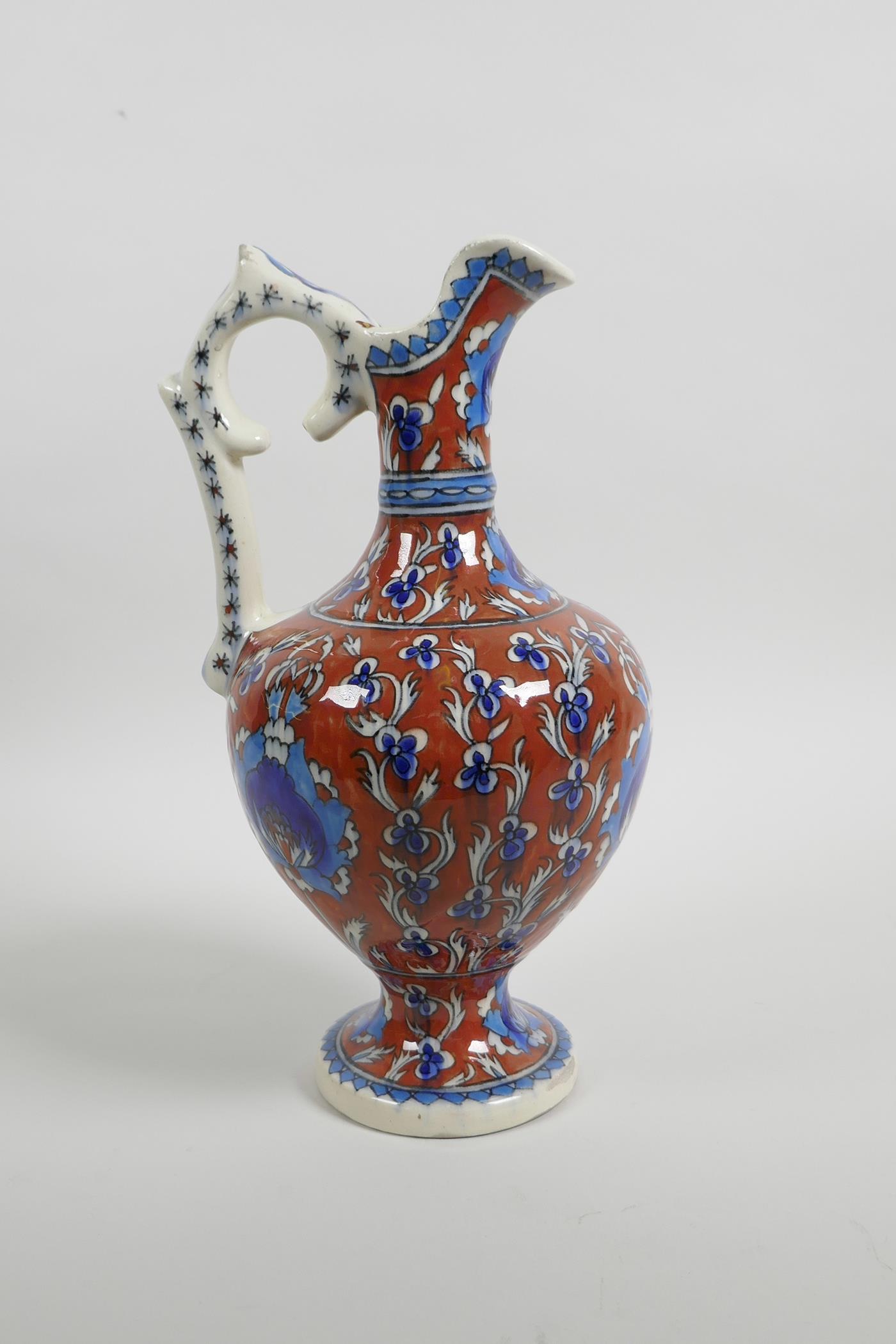 An early C20th Turkish Kutahya pottery ewer with traditional floral decoration, repair to handle, 10