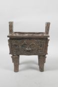 A Chinese bronze archaic censer with two handles, the sides with relief mask decoration, 8" high