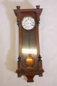 A C19th walnut cased weight driven Vienna wall clock with white enamel face and Roman numerals,