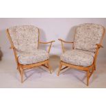 A pair of Ercol Windsor 203 (blonde) armchairs, in beechwood, dating from the early 1970s, featuring