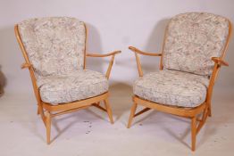 A pair of Ercol Windsor 203 (blonde) armchairs, in beechwood, dating from the early 1970s, featuring