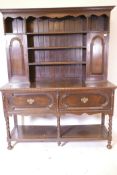 An early C20th Georgian style oak dresser, the upper section with fielded panel doors and open