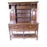 An early C20th Georgian style oak dresser, the upper section with fielded panel doors and open