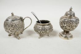 A late Victorian Anglo-Indian solid silver (tested) three piece condiment set, with embossed