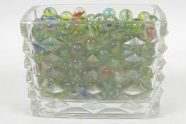 A rectangular glass vase with applied diamond decoration, containing a quantity of colourful