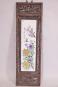 A Chinese famille rose porcelain panel in a carved and pierced hardwood frame, decorated with