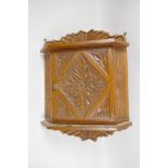 A Continental carved oak corner cupboard of small proportions with radial and floral carved designs,